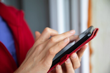 Female hands touching the phone in a red case