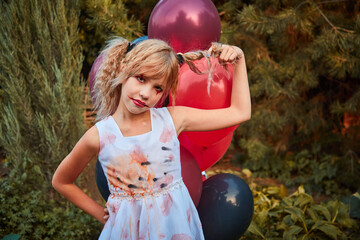 One girl aged 9 in a Halloween dress with red and black balloons in the open air in the Park, emotions, pampering, play. The concept of a fabulous autumn Halloween holiday