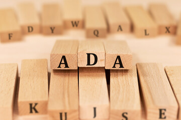 Word ADA Americans with Disabilities Act on wooden blocks beige background top view, scattered cubes around random letters