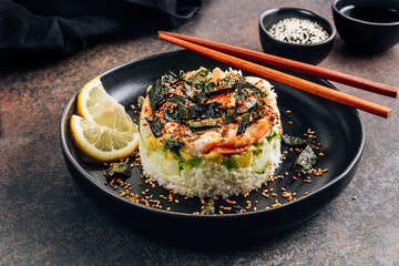 Spicy shrimp sushi stacks with layers of sushi rice, cucumbers and avocado in addition to the spicy shrimp and furikake on dark backgraund. Selective focus