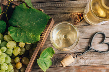 Two glasses of white wine and grape on vintage wooden table. Top view