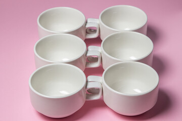 White cups on a pink background. Lots of empty tea cups.
