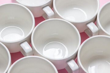 White cups on a pink background. Lots of empty tea cups.