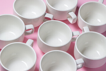 White cups on a pink background. Lots of empty tea cups.