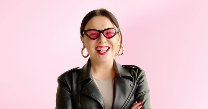 Portrait unusual stylish woman inflates bubble from chewing gum and bursts in pink sunglasses. Blowing bubble gum and smiles.