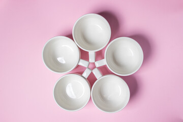 White cups on a pink background. Lots of empty tea cups.