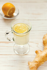 Drink hot tea with ginger-lemon on white wooden background, prevention of colds. Selective focus