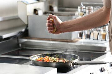 Male chef cooking tasty food on stove in restaurant