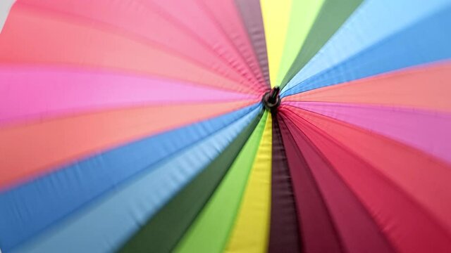 Beautiful young girl with dyed hair and a short haircut. Opens a bright colored umbrella and twists it in front of the camera.