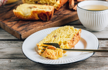 Loaf of banana bread on a wooden cutting board with cup of tea on rustic wooden table. Selective focus