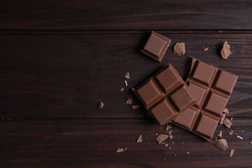 Delicious milk chocolate on wooden table, flat lay. Space for text