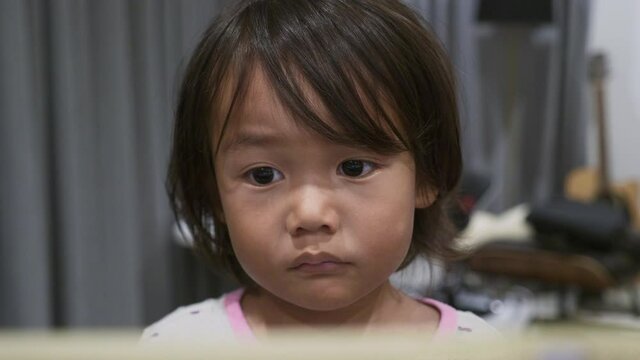 Medium Close of a 2 year old toddler watching a video on an iPad, tablet.