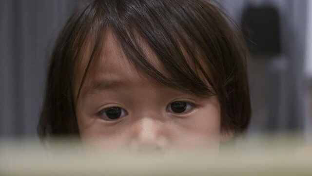 Close Up of a 2 year old toddler watching a video on an iPad, Tablet.