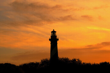 Silhouetted lighthouse at dramatic, warm, vivid, fiery  yellow and orange sunset at twilight in St. Augustine, Florida.