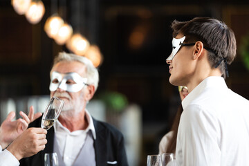 business man in fancy mask holding wine glass talking with colleagues. office employee having seminar party. corporate company meeting in New Year celebration concept