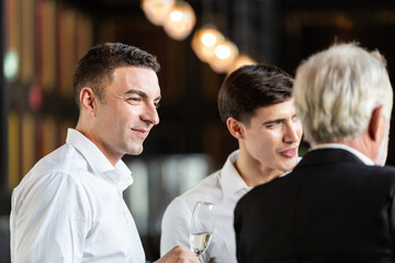 business man holding wine glass talking with colleagues. office employee having seminar party. corporate company meeting in New Year celebration concept