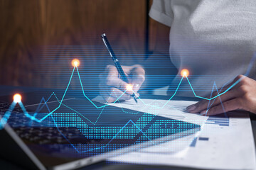 Woman signs agreement. Financial market chart and graph hologram. Double exposure . Business...