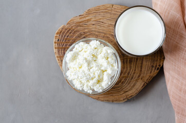 Homemade milk and cottage cheese on a wooden slice on a gray concrete background. Fermented, protein foods and drinks. Flat lay