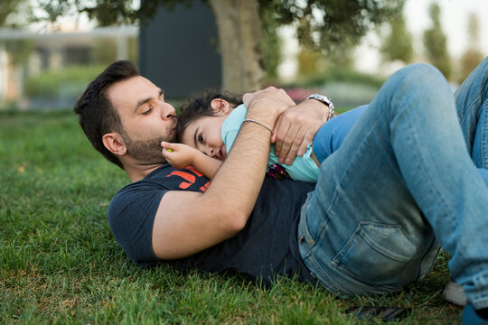 dad hugs daughter on the lawn in the park