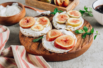 Healthy snack wholegrain rice crispbread crackers, figs and ricotta cheese on a wooden board. Selective focus