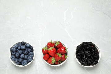 Different ripe berries on light marble table, flat lay. Space for text