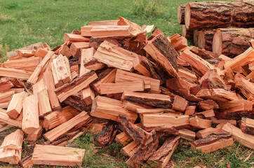 Firewood is stacked in autumn. Chopped pile of wood. Lots of wood from logs. Preparation of firewood for the winter. background texture pattern with stacked dry chopped firewood. Trees in the sawmill