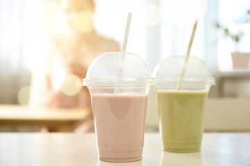 Tasty fresh milk shakes in plastic cups in cafe
