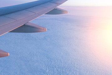 Passenger plane flying above the clouds. View from the wing of the plane. Travel concept