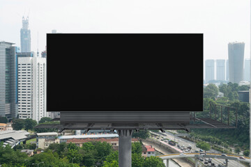 Blank black road billboard with Kuala Lumpur cityscape background at day time. Street advertising poster, mock up, 3D rendering. Front view. Concept of marketing to promote or sell services or ideas.