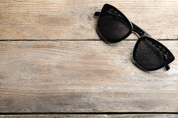 Fototapeta na wymiar Stylish sunglasses on wooden background, top view. Space for text