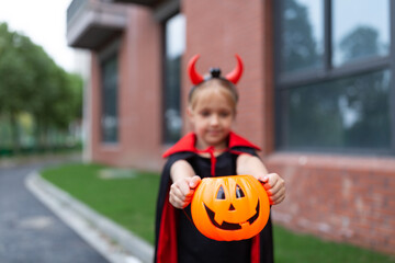 Little Girl in costume of devil with red horns in park. Happy Halloween concept
