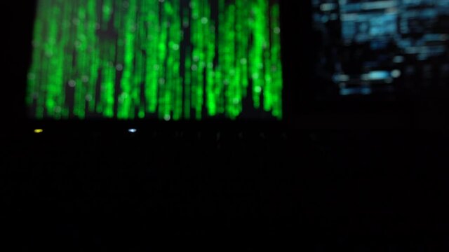 Cybersecurity concept. Hacker code on two computer screens with green blinking keyboard infront