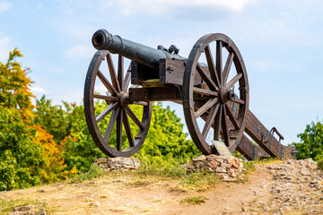 Historic cannon in front of Prison Tower and Eastern Gate of Checiny Royal Castle medieval fortress in Swietokrzyskie Mountains near Kielce in Poland
