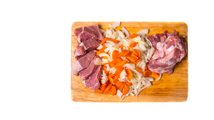 Pork meat cut into pieces with carrots and onions on a cutting Board on a white background with a place for writing,side view