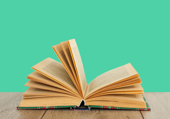 Open book textbook in colorful cover on a green background. Back to school distance home education.Quarantine concept of stay home.