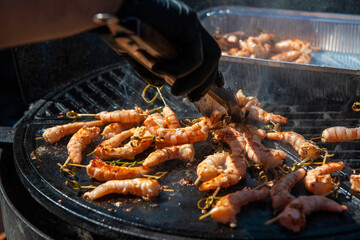 A professional cook prepares shrimps on the grill outdoor, food or catering concept