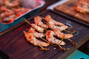 A professional cook prepares shrimps on the grill outdoor, food or catering concept
