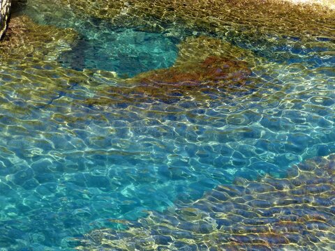 Turquoise clean sea water surface. rocky seabed. glittering ocean texture.