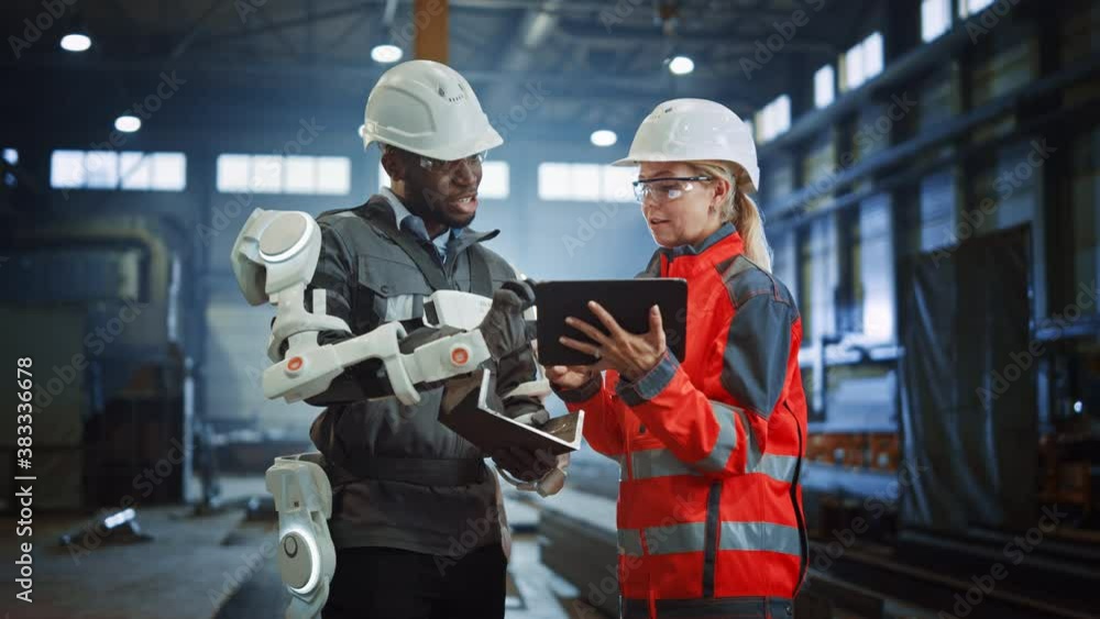 Leinwandbilder Futuristic Concept of a Manual Labor Worker in a Bionic Exoskeleton Prototype Working in a Factory. Heavy Industry Engineer Monitors the Powered Suit on an African American Assistant.