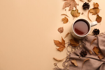 Flat lay composition with cup of hot drink, scarf and autumn leaves on beige background, space for...