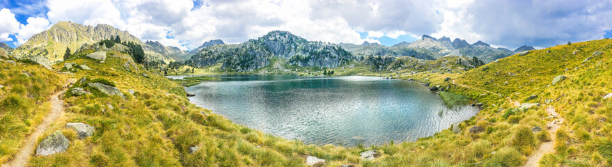 Panoramic view of a beautiful natural lake on a hiking trail in the mountains. Llac del Circ de Colomers, Pirineus, Salardú, Naut Aran, Val d'Aran, Lleida, Catalonia, Spain. - obrazy, fototapety, plakaty