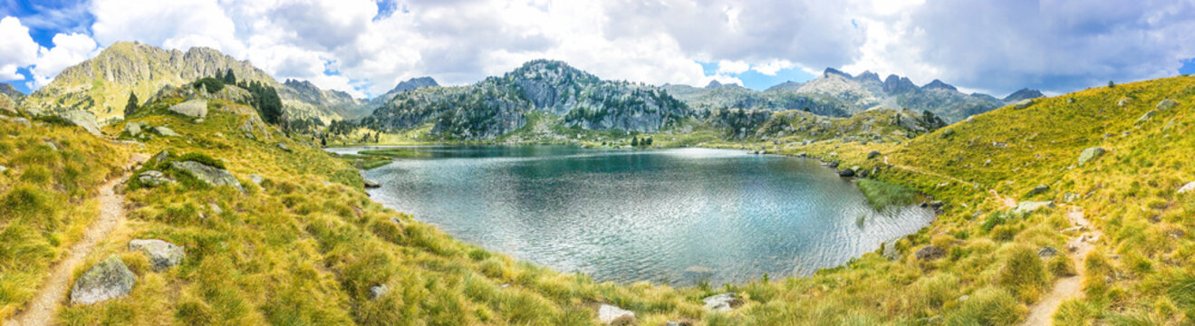Panoramic view of a beautiful natural lake on a hiking trail in the mountains. Llac del Circ de Colomers, Pirineus, Salardú, Naut Aran, Val d'Aran, Lleida, Catalonia, Spain.