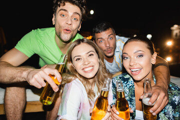 Selective focus of couples holing beer bottles during party outdoors at night