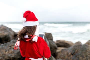 Obraz premium little girl in santa suit on the beach
