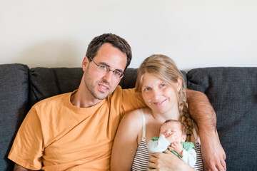 Happy parents with newborn on sofa