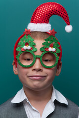 Portrait of happy little boy wearing headband with Santa Claus Hat and funny glasses with Christmas trees