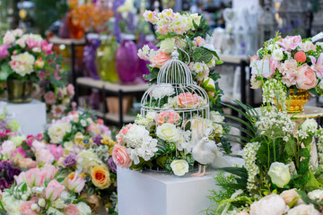 A flower arrangement of artificial roses, a metal birdcage and a fabulous white bird. Home interior decoration, textile rose flower pink white with green leaves