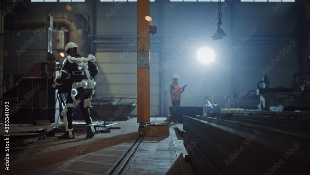 Poster black african american engineer is testing a futuristic bionic exoskeleton and picking up metal obje