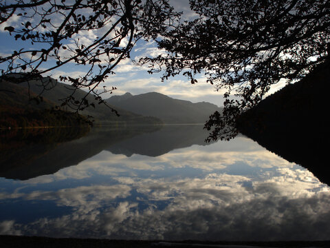 Nubes, Arboles y monta&ntilde;as reflejo en espejo  lago Tromen Patagonia Argentina