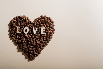 Coffee beans in the shape of a heart and the inscription love on a background